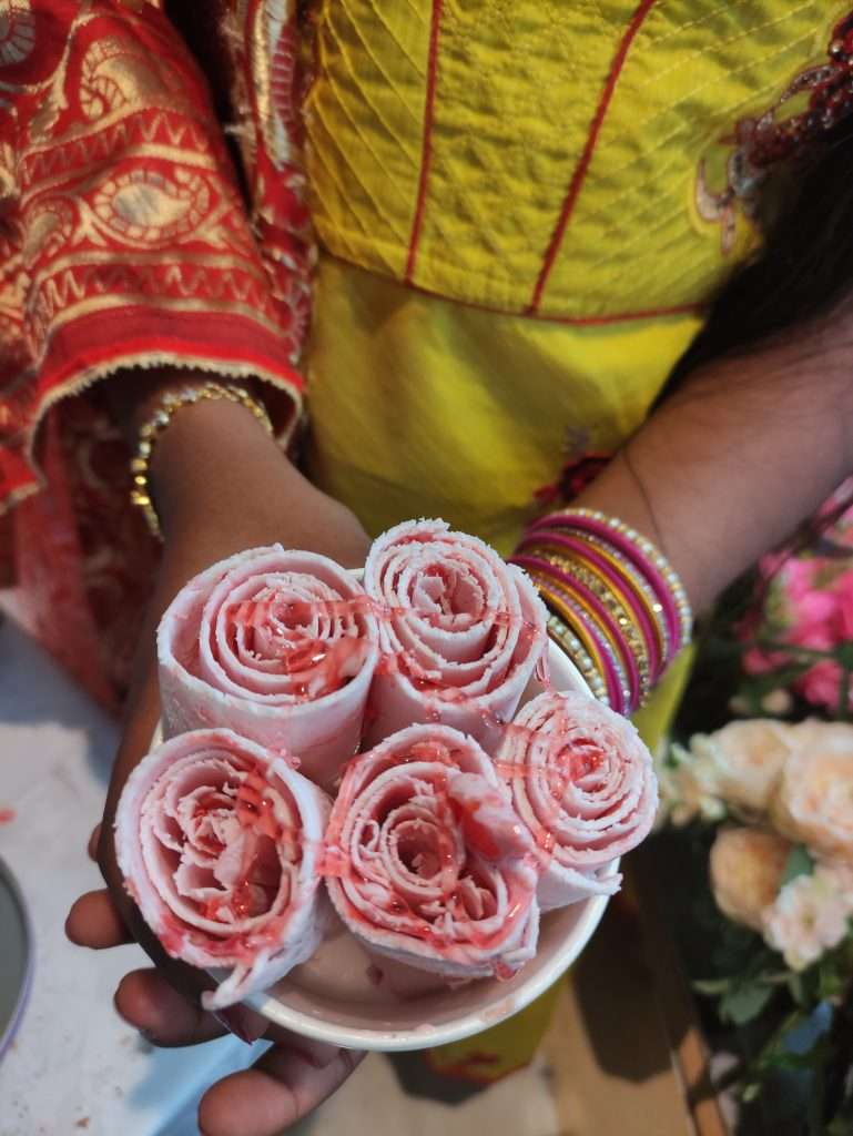 Asian girl in Hindi dress holding a cup of strawberry and Meringue ice cream rolls