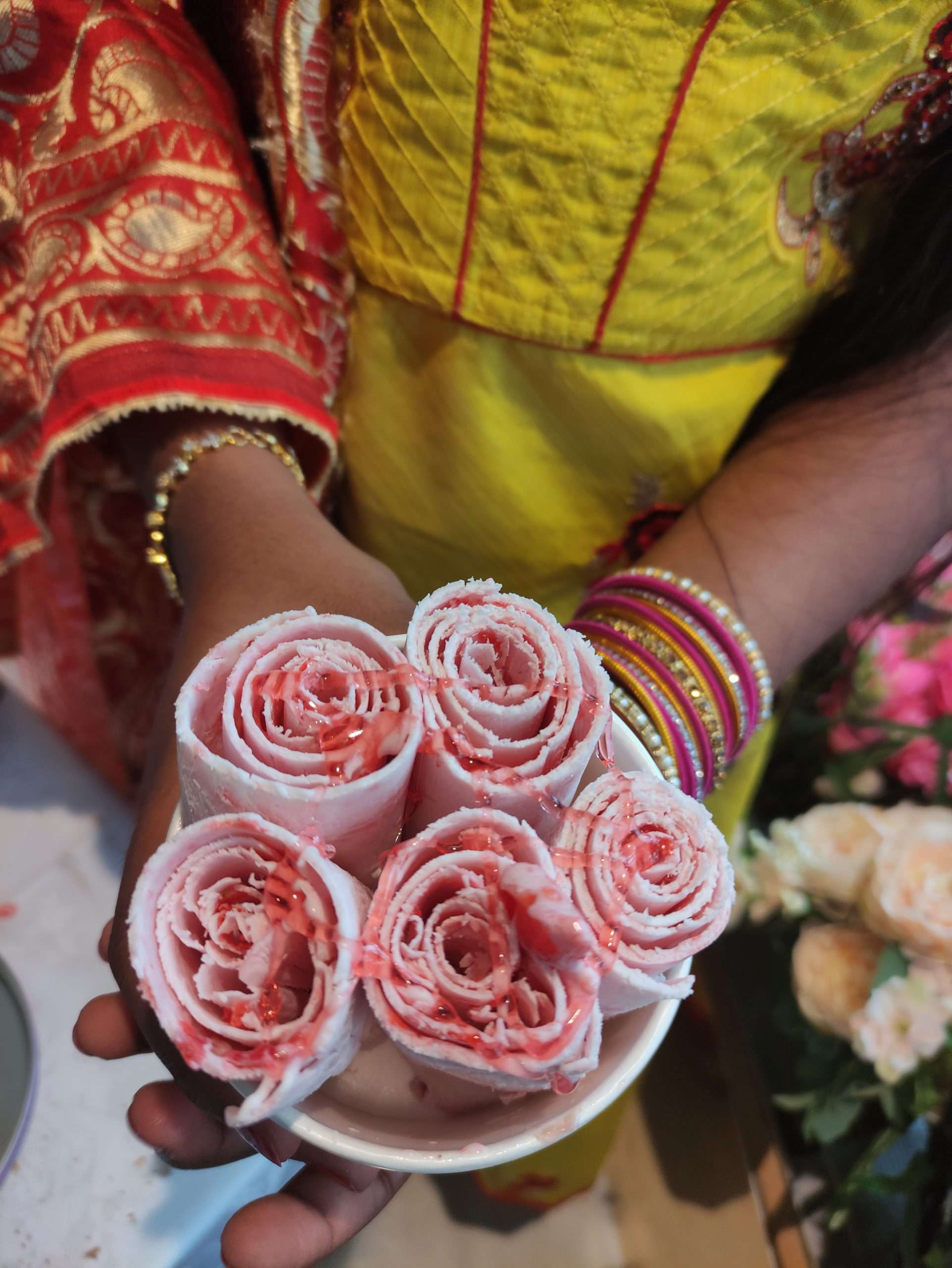 Asian girl in Hindi dress holding a cup of strawberry and Meringue ice cream rolls